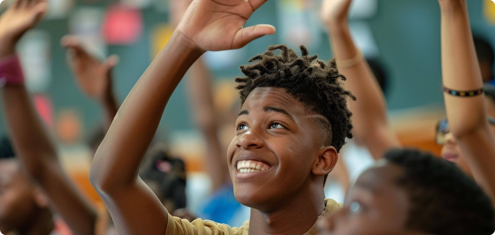 Student who is raising his hand and smiling in class