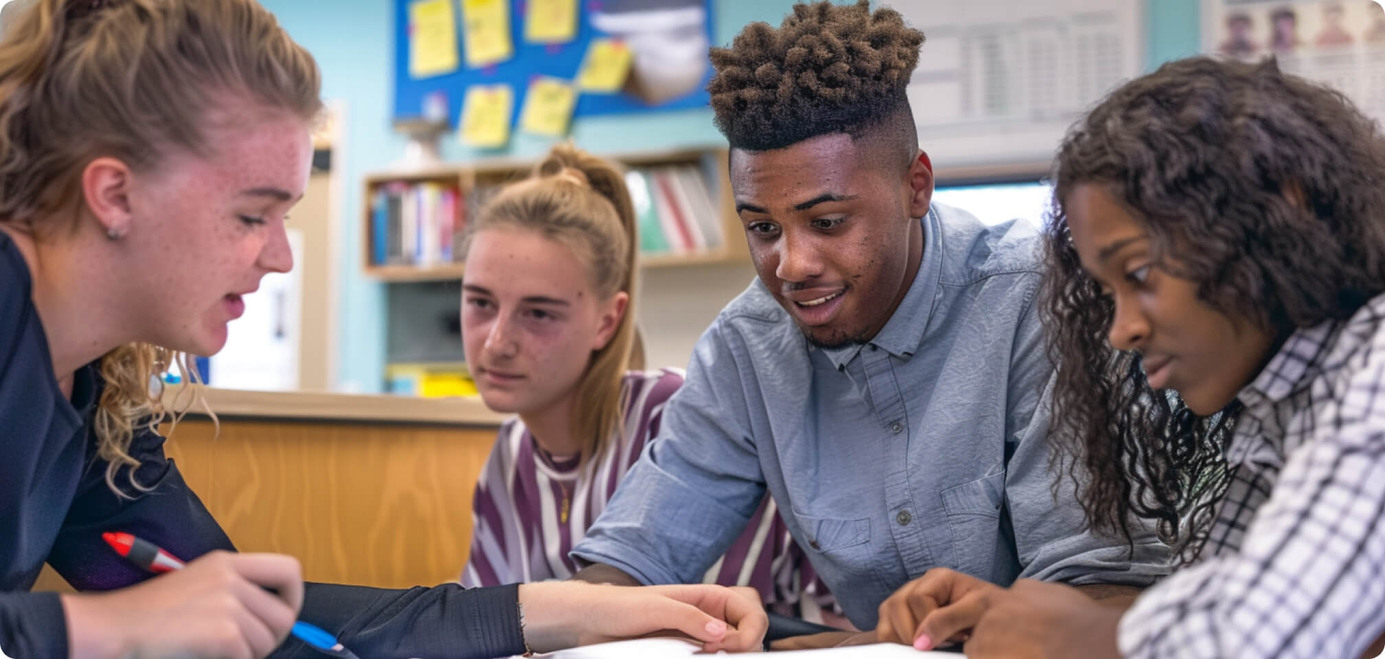 a group of students working together at a desk smiling