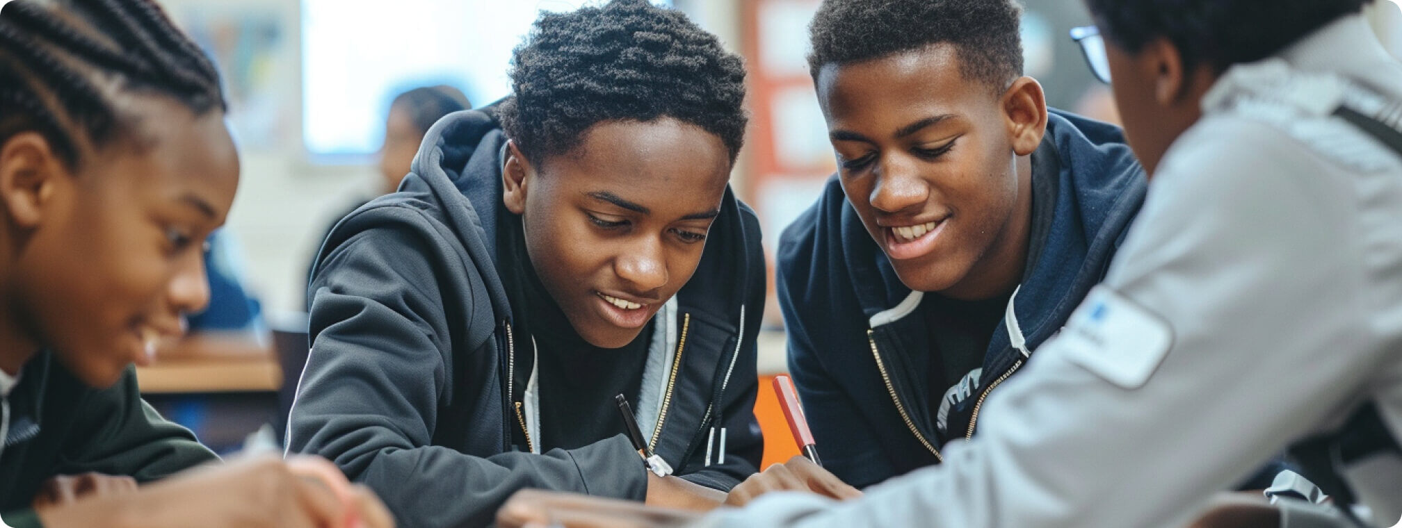 a group of students working together at a desk smiling 2