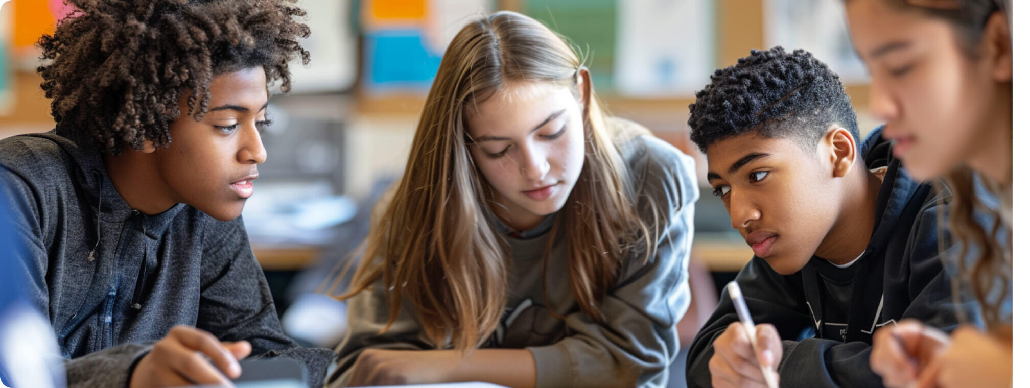 a group of students working together at a desk smiling 3