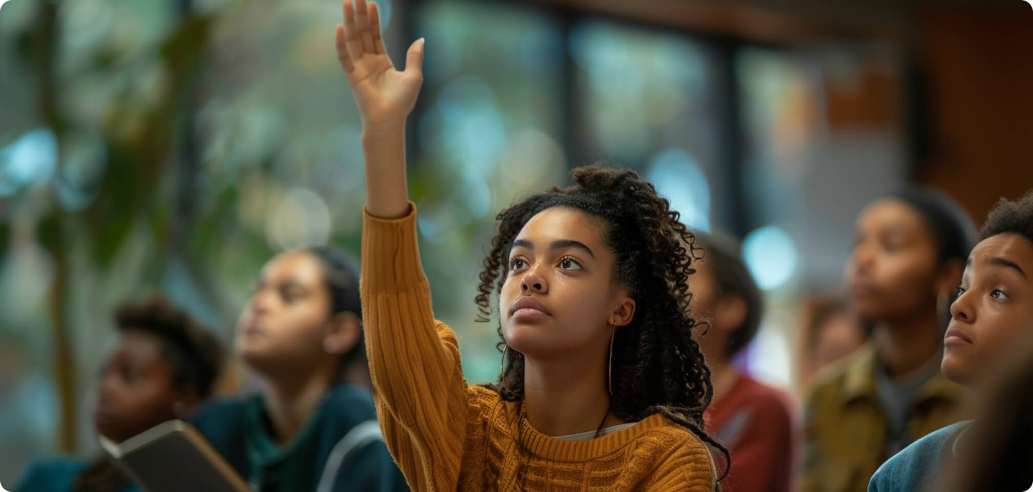 a student raising his hand in a classroom to ask a question