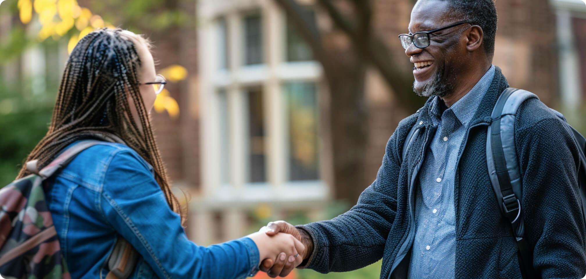 a student shaking a teachers hand a smiling