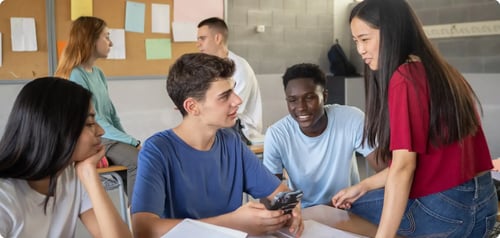 A diverse group of students all working at a desk together