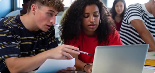 A diverse group of students all working at a desk together