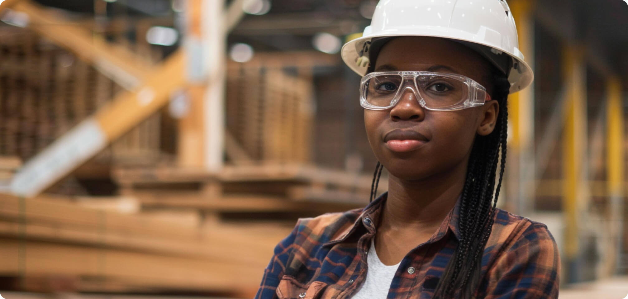 a student in safety glasses and a hard hat standing in a warehouse