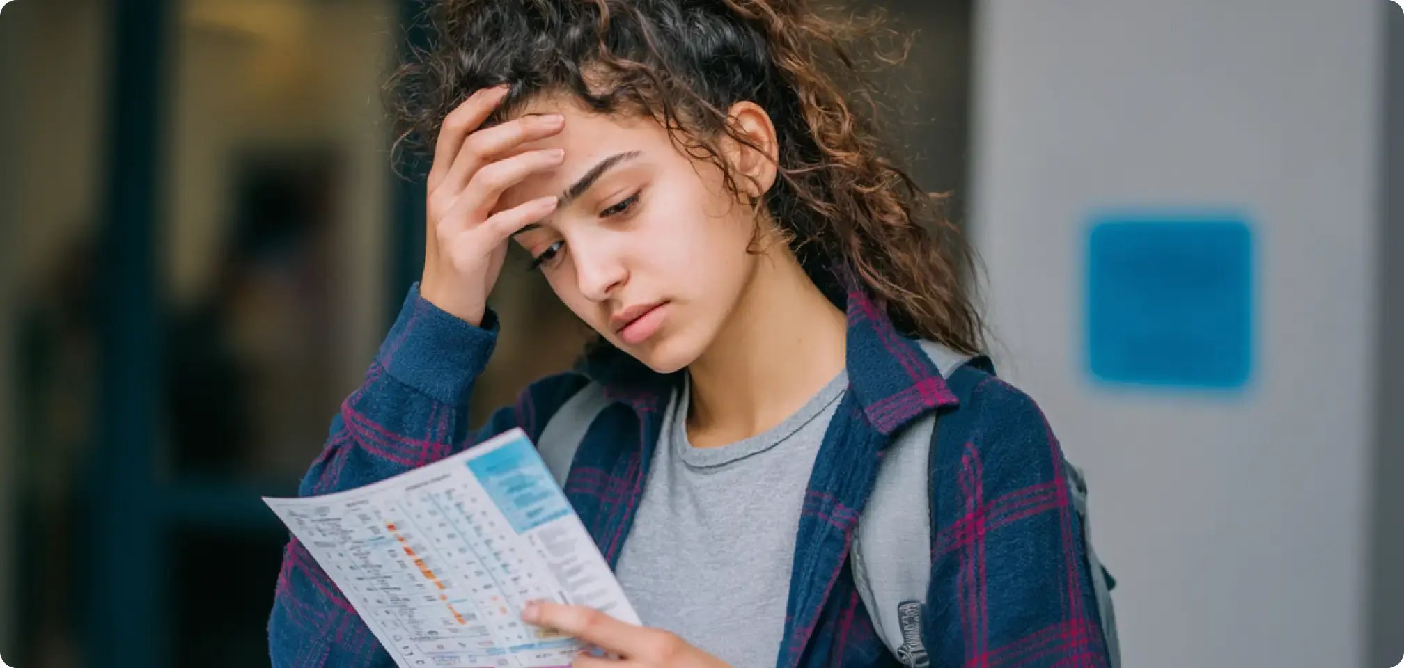 a student holding a report card looking stressed